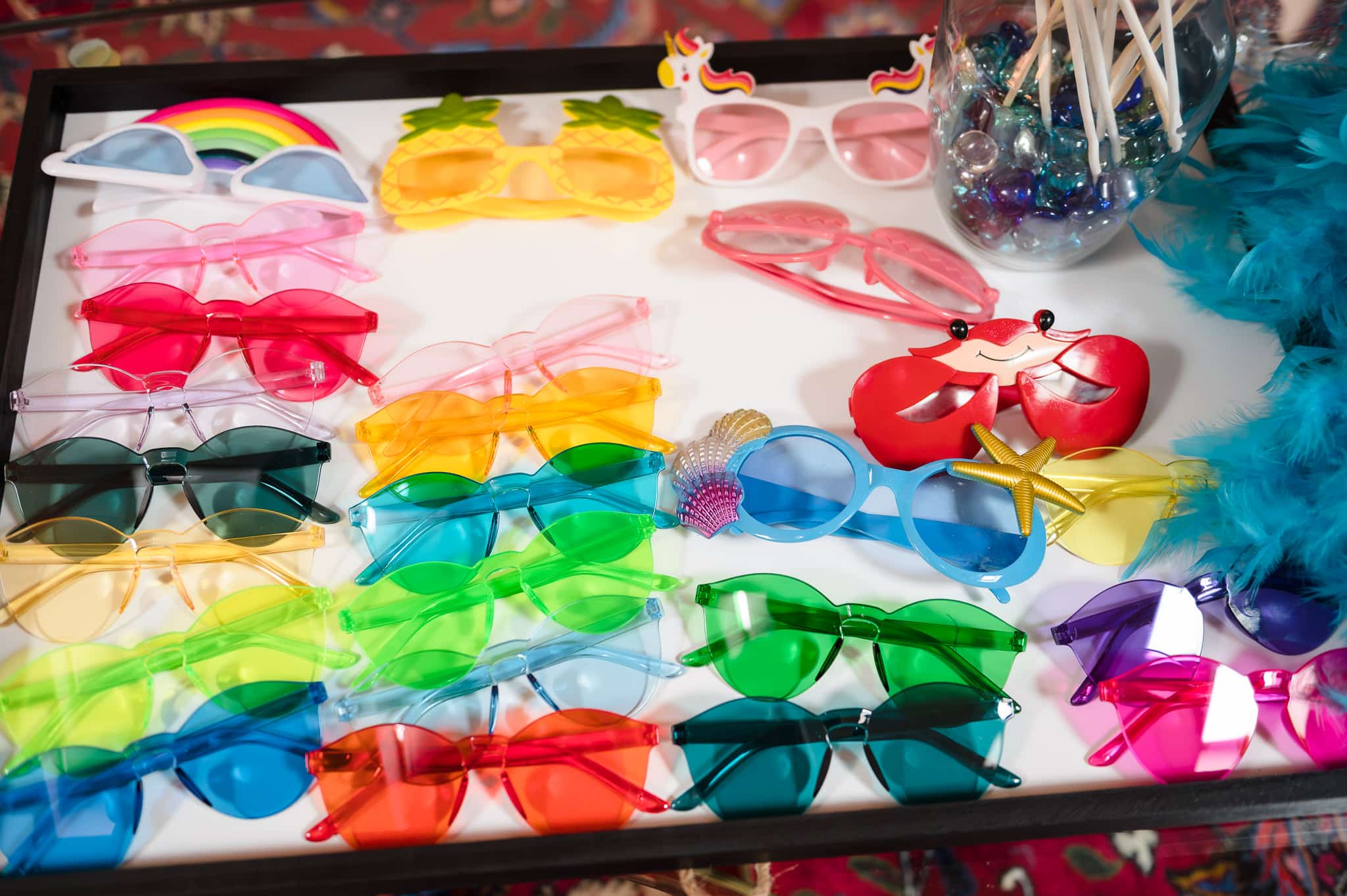 A tray filled with fun and silly sunglasses of different colors to be worn while taking photos in a photo booth.