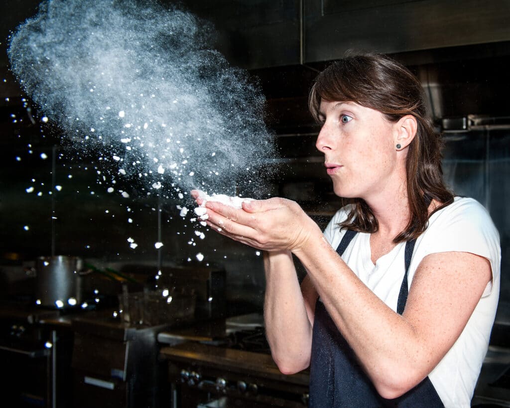 Chef Katie Weinner blows a powdery handful of maltodextrin into the air
