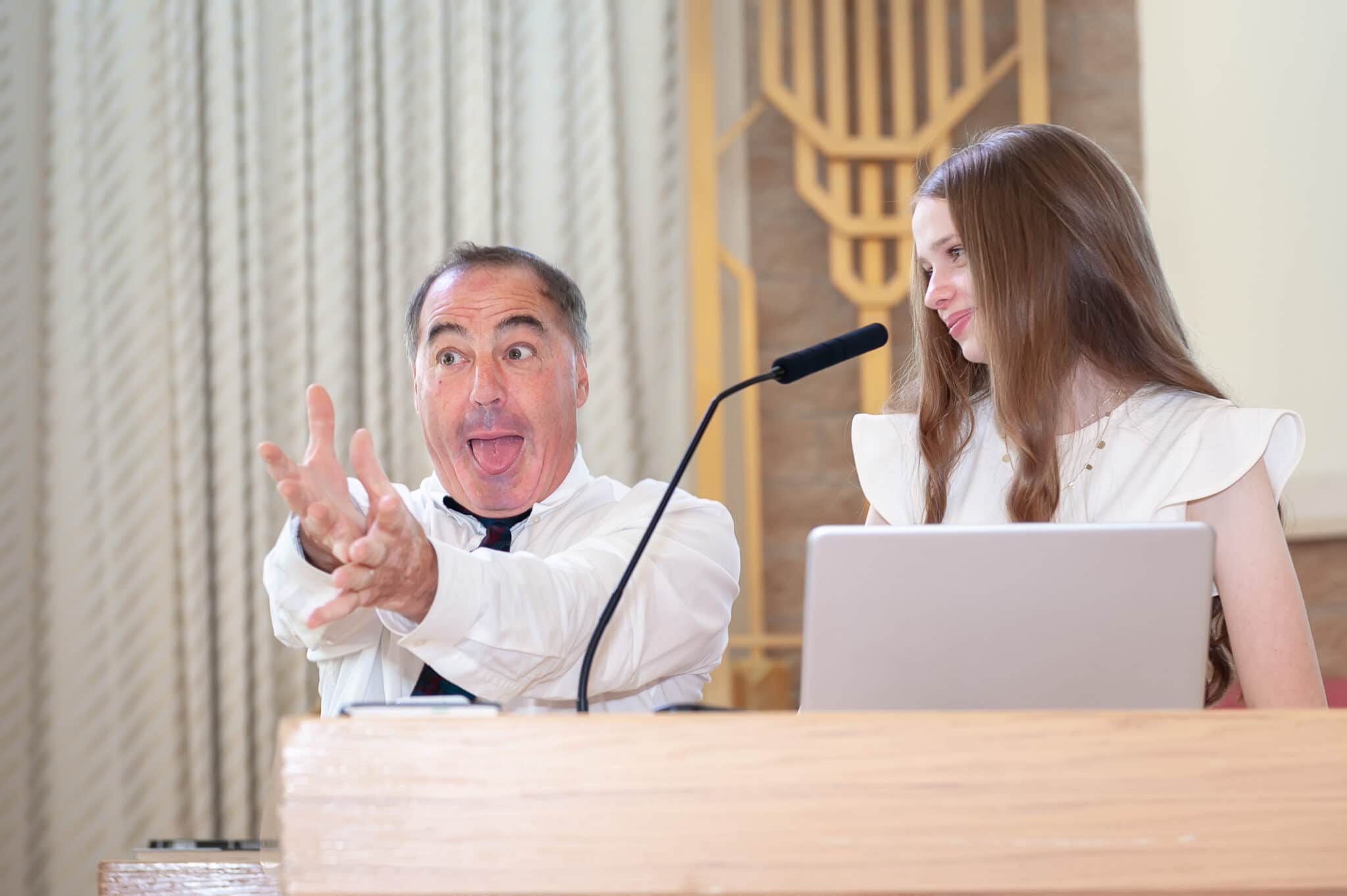 A young girl looks on as her mentor gestures that she project her voice more during her bat mitzvah rehearsal in Denver.