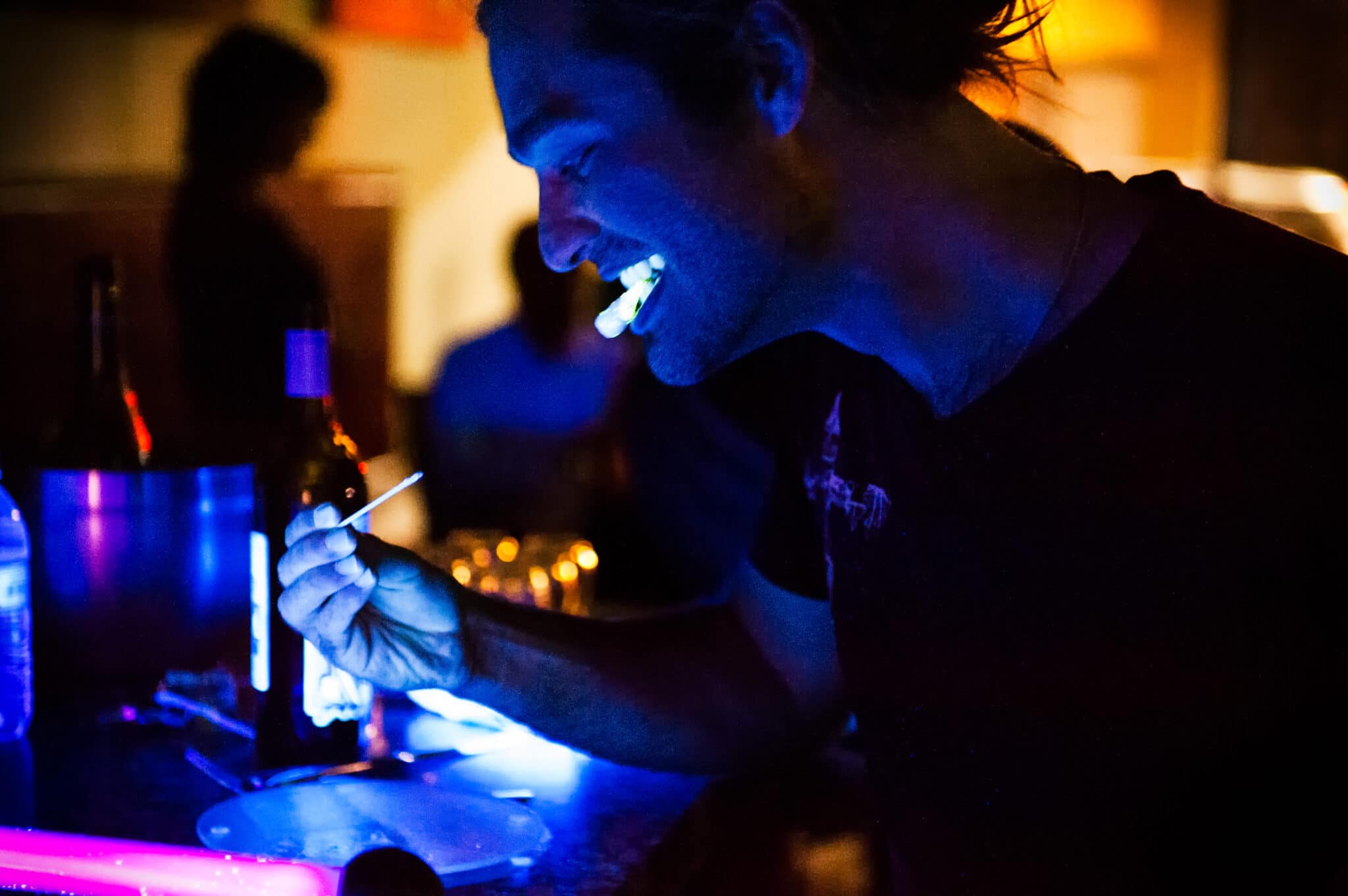 Black light illuminates a guest eating food designed to glow in that type of illumination at a restaurant pop-up event.