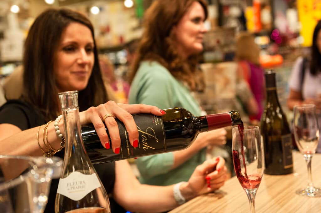 A woman pours a glass of red wine for a tasting during the opening of total wine.