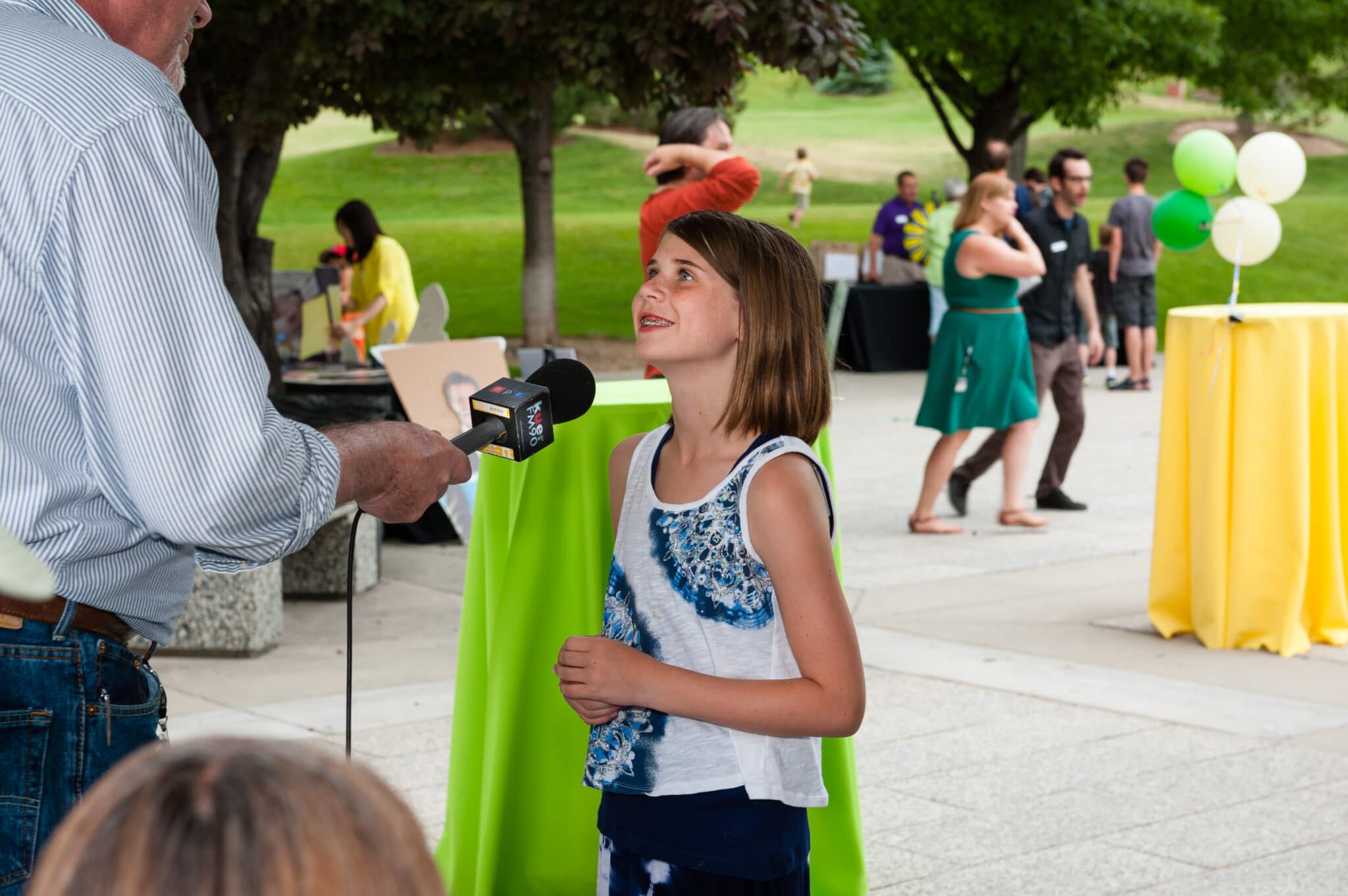 A young girl speaks into a microphone and talks about why she likes public radio at the KUER summer event.