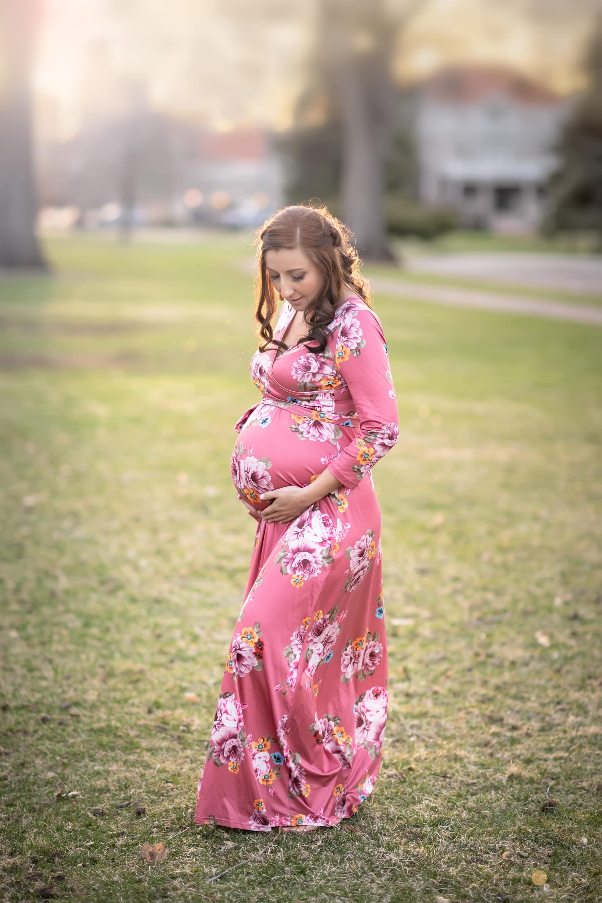 Best maternity photo sessions take place in the outdoors like this session at City Park where the mother gently holds her rounded belly.