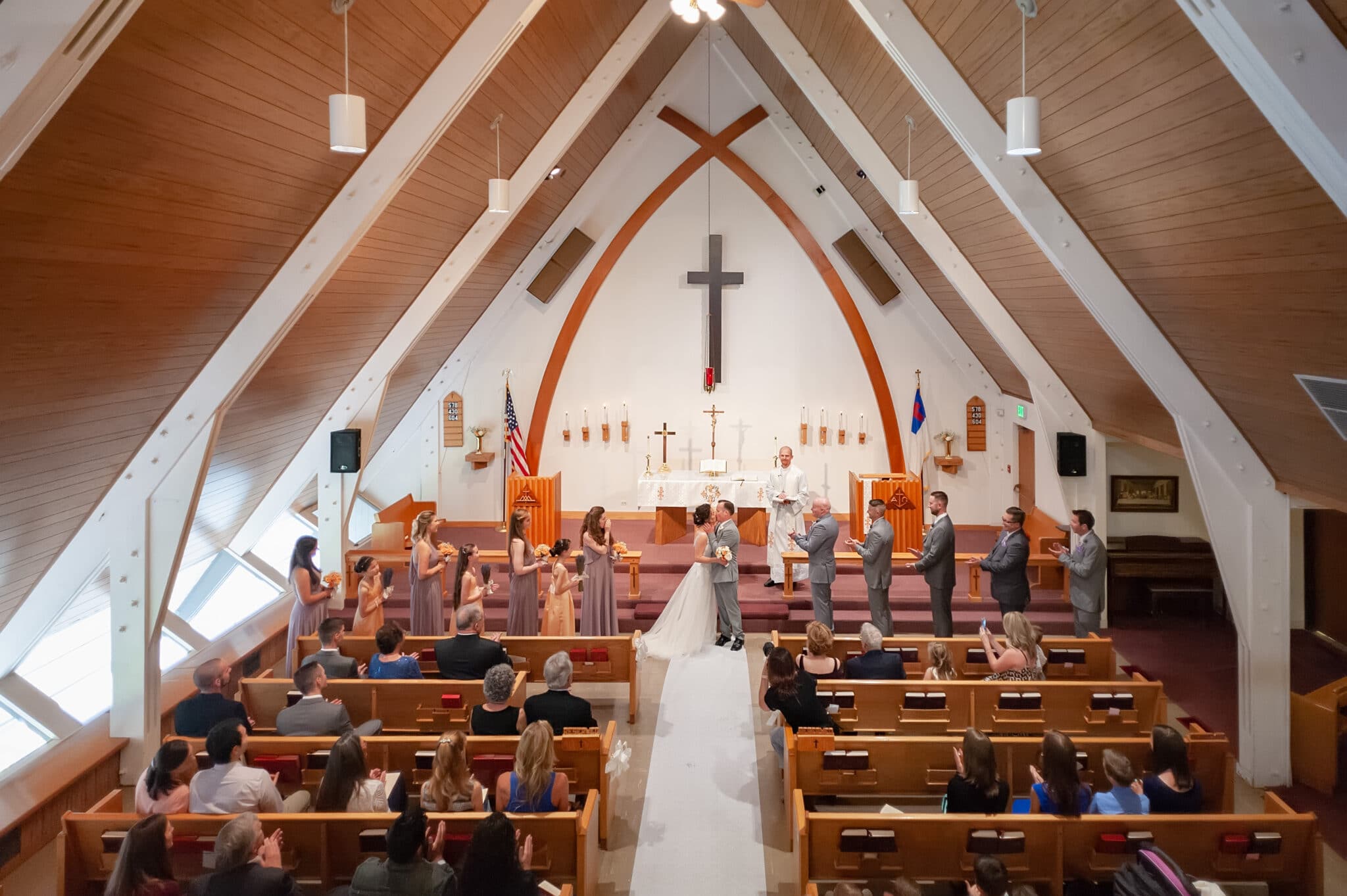 A balcony view of a bride and groom kissing in church following their wedding ceremony.