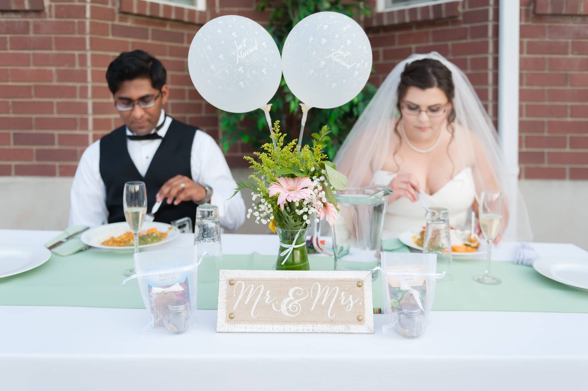At the head table labeled Mr & Mrs, the bride and groom enjoy their meal together.