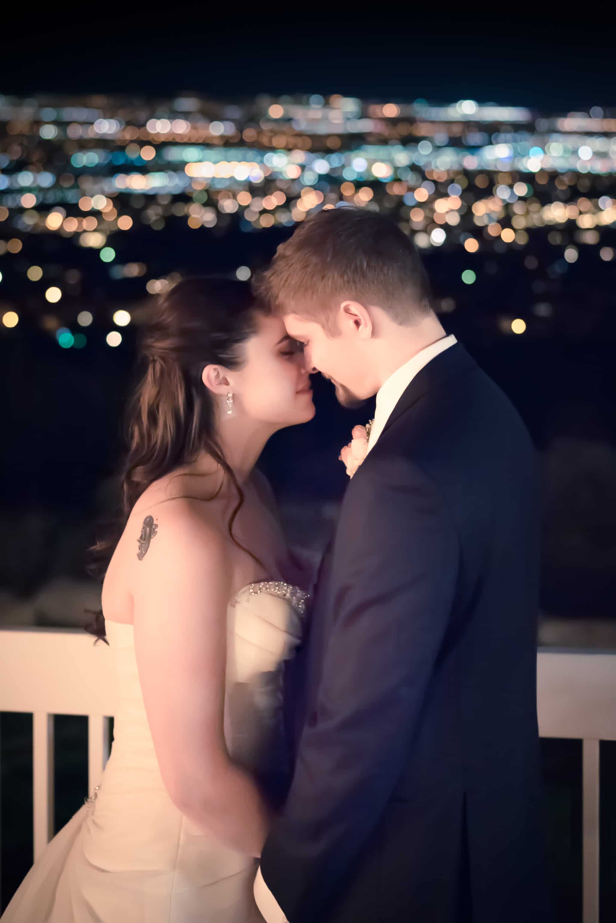 Evening portrait of newlyweds with city lights twinkling in the background.