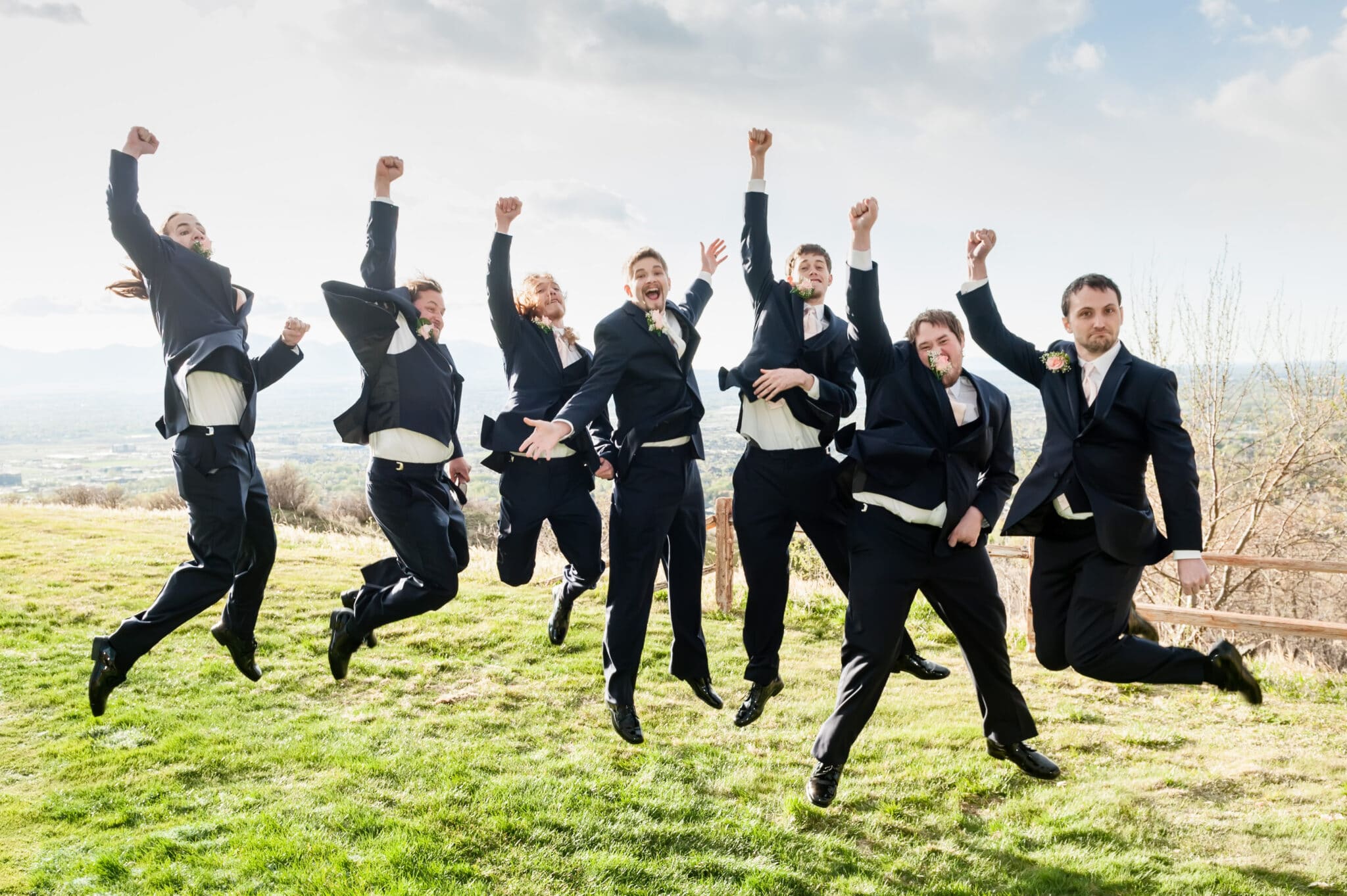 Jumping groom and groomsmen at an outdoor wedding at a golf course.