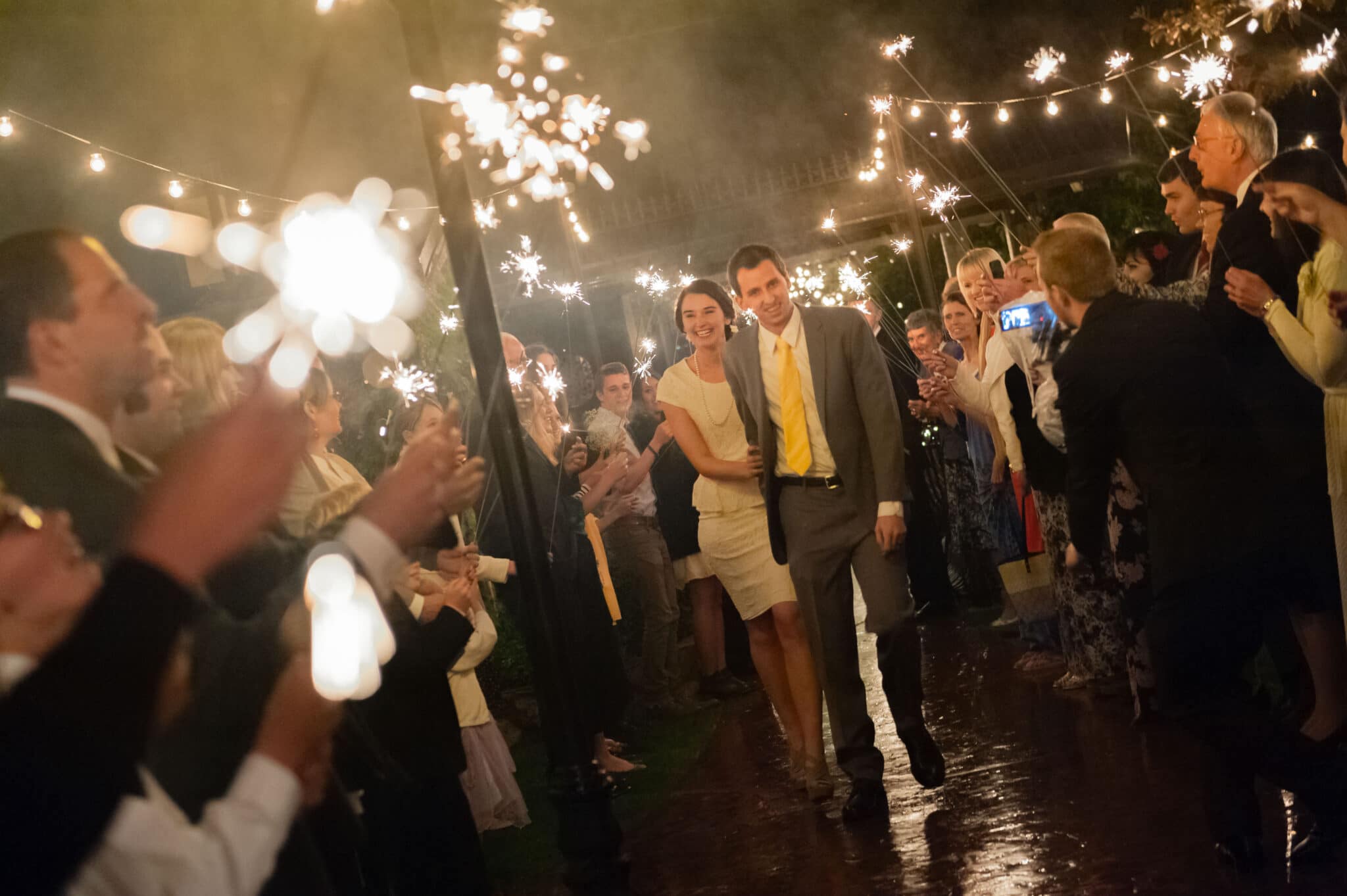The bride and groom exit their wedding amid sparklers held by family and friends.
